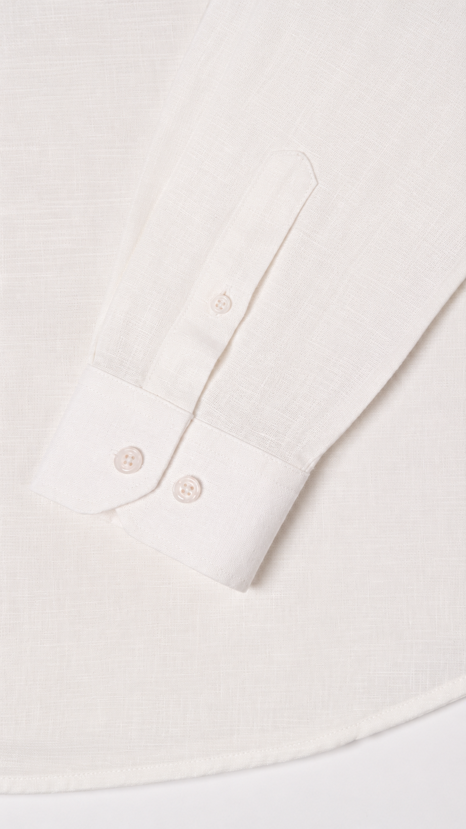 Close-up of a white long-sleeve shirt showing the buttoned collar and part of the sleeve, with a subtle textured fabric.